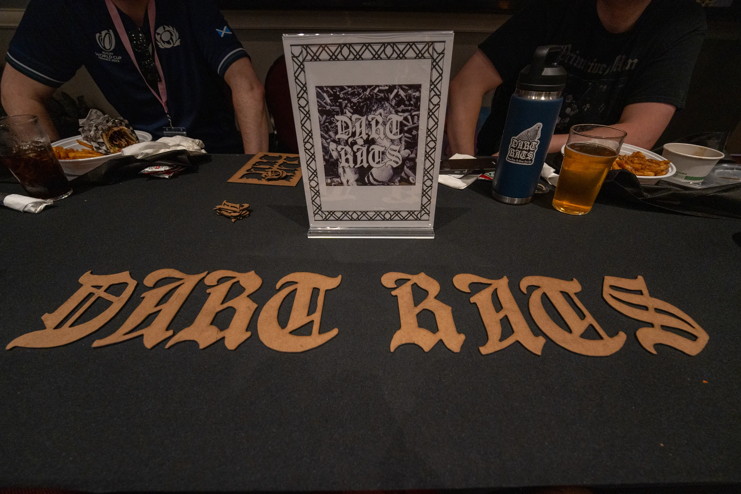 The Dart Rats table at Dungeon Fest 2026, set with its wooden sign, dice, and drinks.