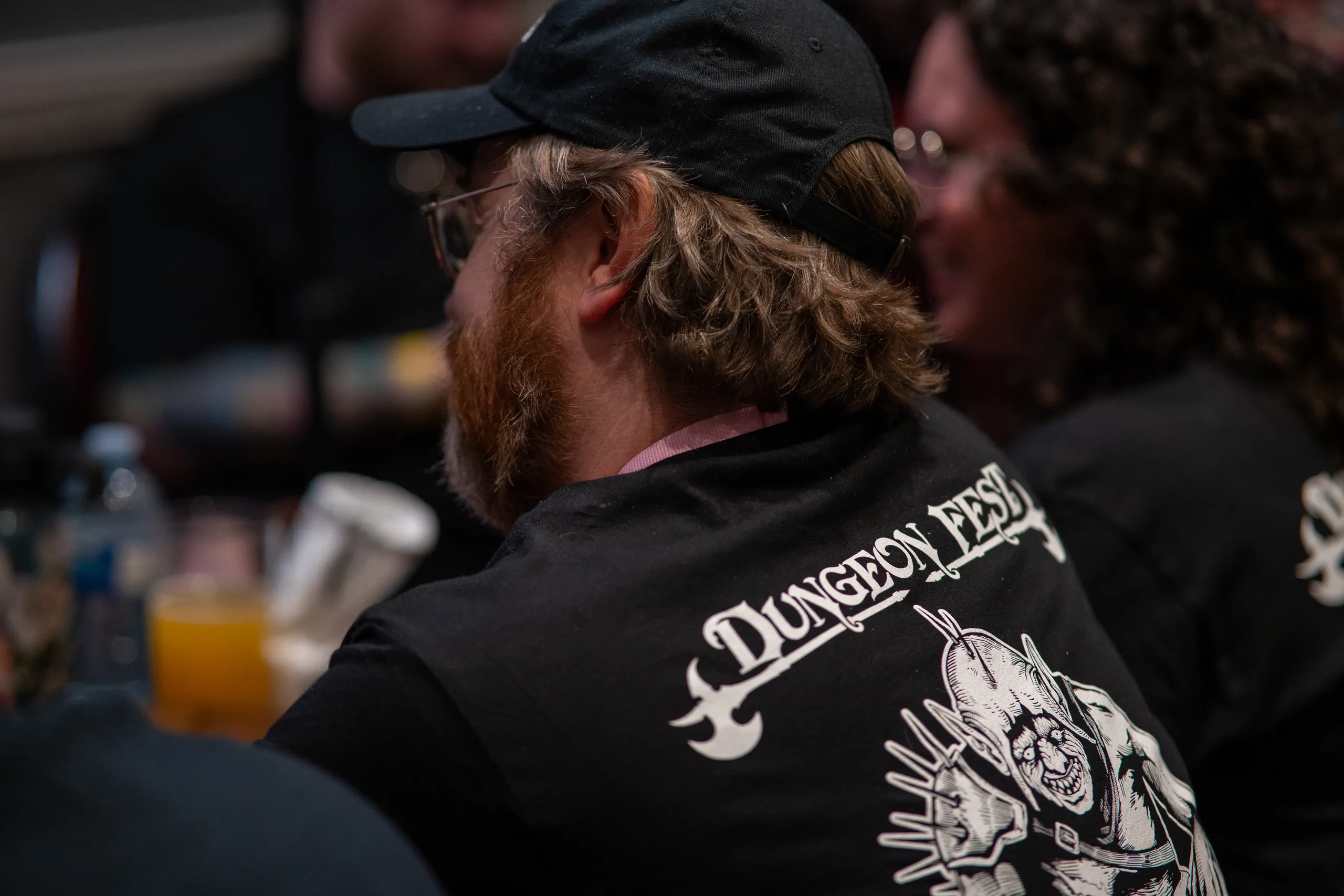 A player in Dungeon Fest merch leaning into a game at the table.