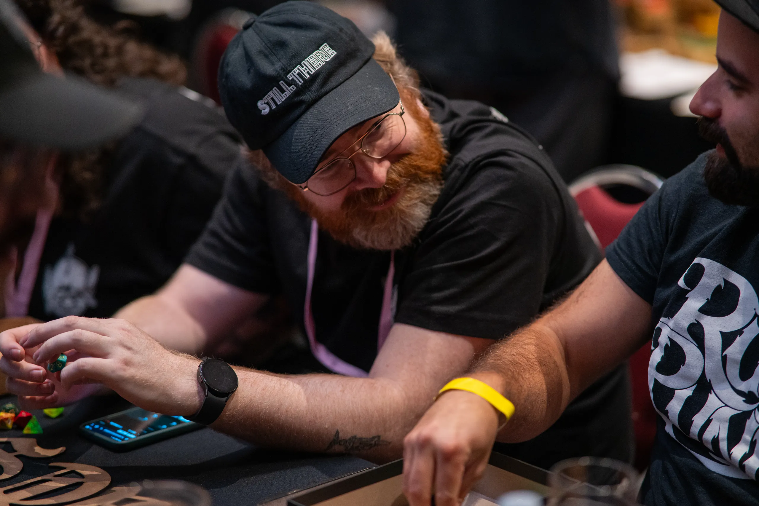A player in a Dart Rats shirt smiling at the table.